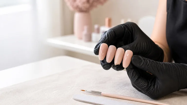 Mani guantate mostrano tip nude con irregolarità, una crepa e un bordo scheggiato
