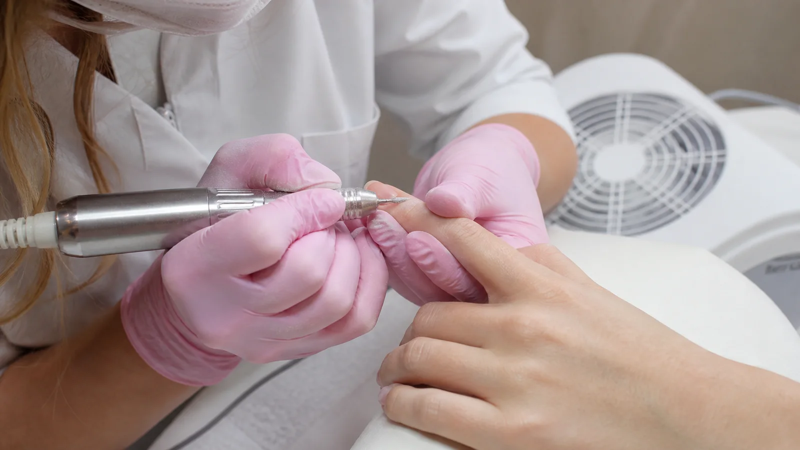 Onicotecnica esegue una dry manicure di precisione su unghie naturali in ambiente professionale