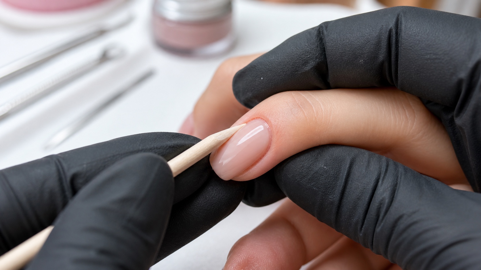 Onicotecnica con guanti neri controlla un piccolo sollevamento laterale su una ricostruzione unghie nude in gel